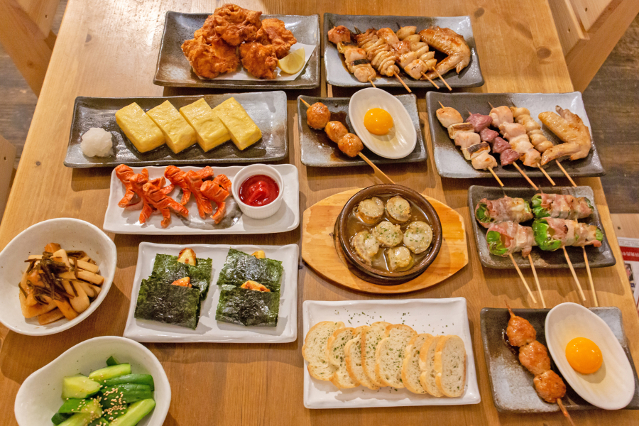 左上から時計回りに「からあげ(大山鶏)」(499円)、「焼き鳥 おすすめ5本盛り合わせ(タレ・塩)」(各980円)、「チーピー肉巻き」(1本 290円)、「特製つくね」(1本 290円)、「帆立のアヒージョ」(599円)、「チーズ磯辺焼き」(399円)、「ごまキュウリ」(299円)、「塩こんぶ大根」(299円)、「赤ウインナー」(399円)、「だし巻きたまご」(599円)